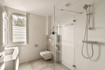 a bathroom with a toilet, shower stall and sink in the corner next to the window that looks out onto the street