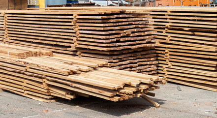Pile of stacked wooden planks at a construction site. Wooden boards, lumber. Industrial edged...