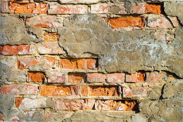 Old brick wall, cement and plaster peel off with wrecked bricks. Background, texture. Close-up.