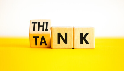 Think tank symbol. Businessman turns wooden cubes and changes the word Tank to Think or vice versa. Beautiful yellow table white background, copy space. Business, think tank concept.