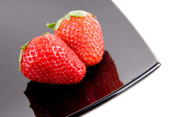 five ripe strawberries on the black plate