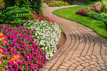 Flowerbeds of vivid colored impatiens border a winding garden path.