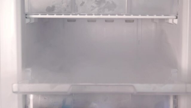 woman hand opens freezer puts in and takes out phone in mist