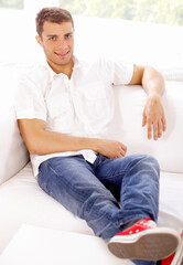 Fototapeta na wymiar Young man sitting on couch in his home
