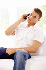 Obraz premium Young man sitting on couch and using cell phone