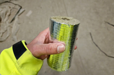 Stück Rohrdämmung in der Hand eines Bauarbeiters