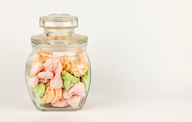 Homemade colored meringue in a glass jar on a white background.