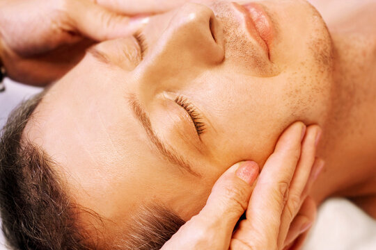 Mature man lying on his back, gets massage,reiki,acupressure on his face, focus on face and hands