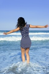 Fototapeta na wymiar Beautiful summer indian brunette girl jumping on the blue beach