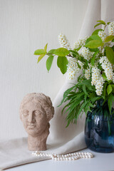 Interior decor. Flowers in a vase, clay sculpture and pearl beads in table. Selective focus