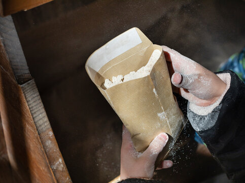 The hands of a child holding a paper envelope filled with wheat flour freshly ground in a traditional mill