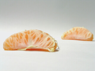 two peeled mandarines on neutral background