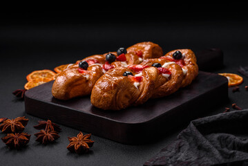 Delicious fresh crispy pastry in the form of a pigtail with strawberries and blueberries