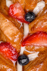 Delicious fresh crispy pastry in the form of a pigtail with strawberries and blueberries