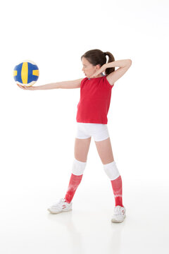 Cute Caucasian girl serving the ball in volleyball