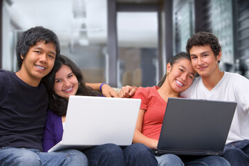 Two couples using laptops and smiling to camera at home