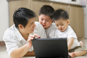 Father introduce technology to his sons using laptop in home