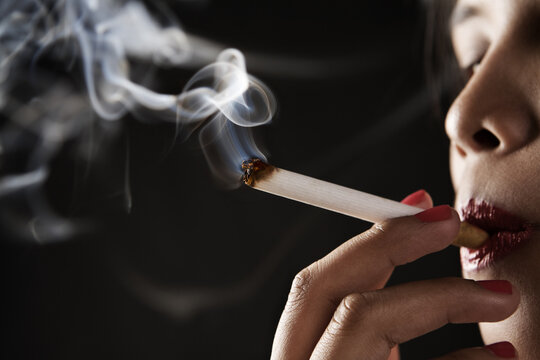 Woman smoking on dark area © Designpics