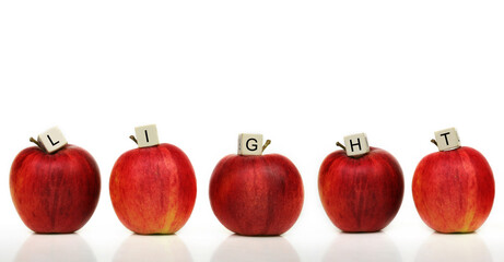 a row of six red apples with cubes of letters on it in front of a white background - light