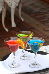 three colorful alcoholic drinks are prepared and served