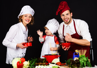 Mother, father and son preparing breakfast or dinner in kitchen. Parents teaching boy how to cook. Happy family cooking together at home. Homemade and healthy food. Little helper with parents cooking.