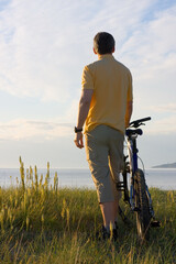 Man standing by his cycle at the sea