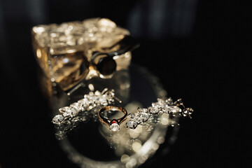 Wedding photo details. Perfume and elegant silver earrings and wedding ring of the bride on a glass...