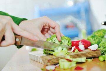 woman preparing healthy food salad with green and red vegetable and knife