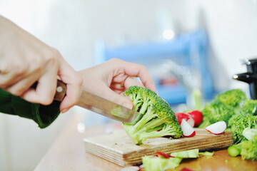 woman preparing healthy food salad with green and red vegetable and knife