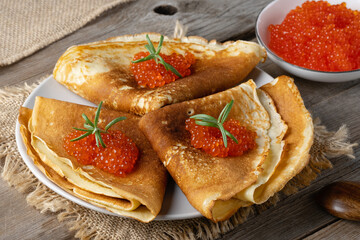 Stack of russian thin pancakes blini with red caviar on an old wooden table. Maslenitsa, traditional Russian blini