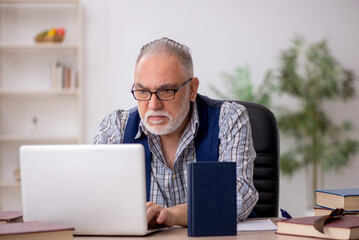 Old male writer sitting at workplace