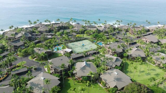 Drone flying above tennis court with active game match, Hawaii USA summer trip 4K. Background of tennis court in tropical lavish green garden of resort hotel area with beach villas or cottages