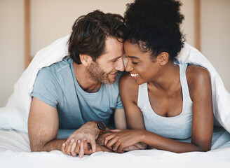 Happy interracial couple, bed and intimate morning in relax or bonding relationship at home. Man and woman smiling in joyful happiness for love, affection or relaxing weekend together in the bedroom - obrazy, fototapety, plakaty