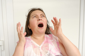 mature woman 50 years old screams, crying from physical or moral pain, psychological suffering...