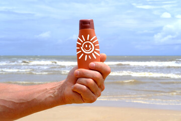 brown mockup sunscreen cream, lotion bottle in tanned male hand, sea waves in background, summer sun protection template scene with cosmetic tube on beach, product presentation, package advertisement