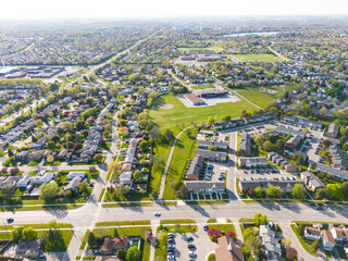 Drone view, sun-drenched Brampton real estate, lush green yards, picturesque houses off...