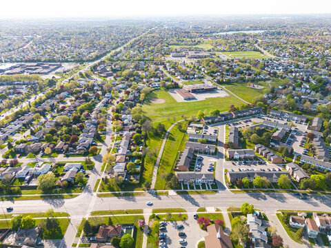 Drone view, sun-drenched Brampton real estate, lush green yards, picturesque houses off Bramalea-Mayfield. Summer in Ontario at its best