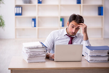 Young male employee and too much work in the office
