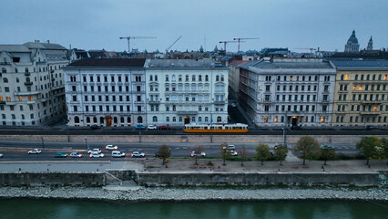 Aerial view of Typical Budapest Tram passing through city neighbourhood during blue hour, Aerial tracking follow shot wide angle, Hungary