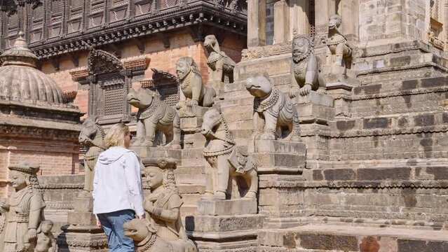 Female tourist walking up the staircase lined with statues at the Siddhi Lakshmi Shikara or Siddhi Laxmi temple in the Durbar Square, Bhaktapur, Nepal