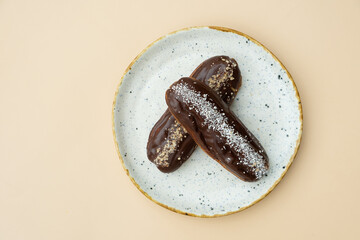 Eclairs in round plate flat lay composition on beige background