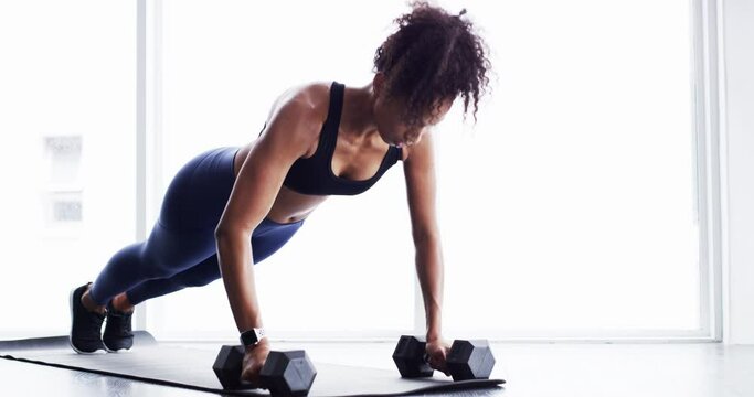 Fitness, woman and push ups with dumbbells, strength with healthy active person and muscle training. Body, exercise routine and sports, strong African female bodybuilder breathing and weights in gym