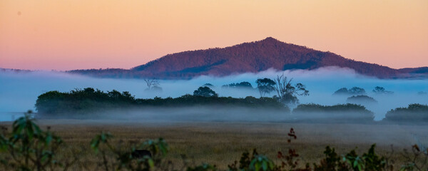 red sunrise above thick mountains covered with thick fog in lamington national park area near...