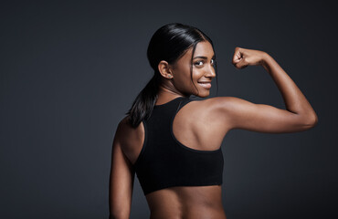 Portrait, happy and woman flexing back in studio isolated on a black background mockup. Strong flex, smile and Indian female athlete with bicep, arm strength or bodybuilder muscle, fitness or workout