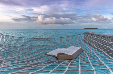 An open book for reading in a beautiful morning atmosphere, in front of the sea on a tropical island
