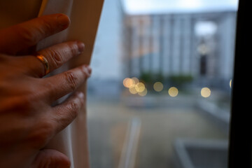 Close-up of men's hand opening the window curtain in the morning