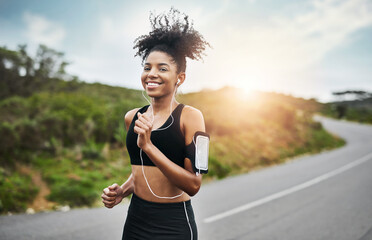Sports, portrait and happy woman running in road with music earphones, workout or cardio routine. Smile, exercise and face of female runner in nature with podcast for training, energy and fitness