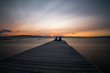 Obraz na płótnie Canvas Pareja de enamorados disfrutando de la puesta de sol en la playa del Trabucador, en el Delta del Ebro.