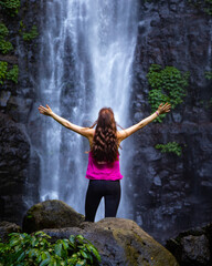 long haired hiker girl standing in frong of large tropical waterfall in lamington rainforest, queensland, australia; famous larapinta falls hidden deep in the jungle