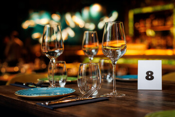 Clear wine glasses on a wooden table in a restaurant.